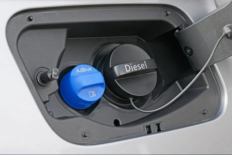 Bidon d'AdBlue posé près du bouchon de remplissage bleu d'un véhicule diesel équipé d'un système SCR