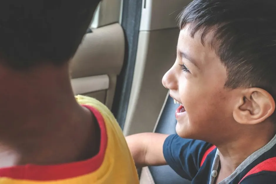 Enfant installé dans un rehausseur voiture avec la ceinture de sécurité passée sur l'épaule
